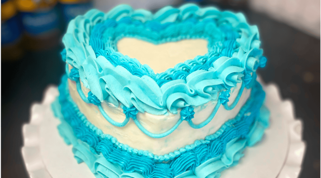 A classy custom cake featuring a heart shape and elegant bordering