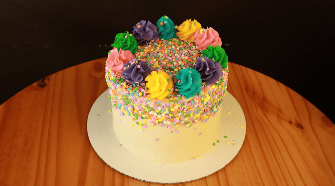 A colorful custom cupcake decked with sprinkles and rimmed with cute flowerets